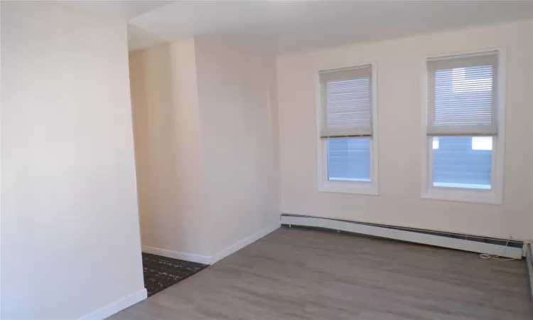 Unfurnished room with a baseboard heating unit and hardwood / wood-style flooring