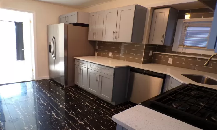 Kitchen with stainless steel appliances, sink, tasteful backsplash, and gray cabinets