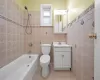 Full bathroom featuring vanity, tile patterned floors, tiled shower / bath, toilet, and tile walls