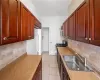 Kitchen featuring decorative backsplash, light tile patterned flooring, stainless steel gas range oven, and sink