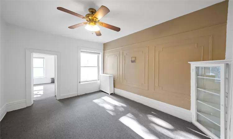 Unfurnished bedroom featuring ceiling fan and dark carpet