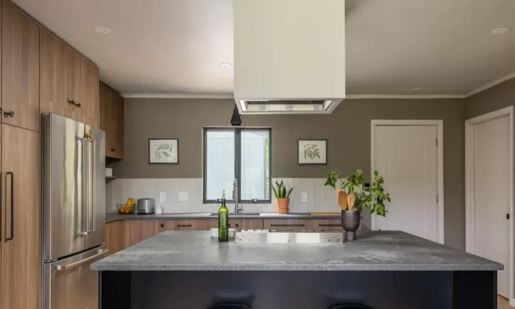 Kitchen featuring sink, high end refrigerator, ornamental molding, and kitchen peninsula