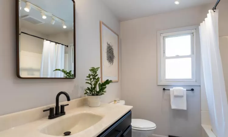 Full bathroom featuring toilet, shower / bath combo, and vanity