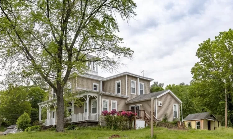 View of front of home featuring a porch and an outbuilding