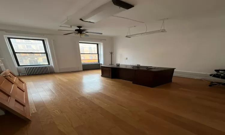 Unfurnished office with radiator, ceiling fan, and light hardwood / wood-style flooring