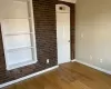 Empty room with brick wall and dark hardwood / wood-style flooring