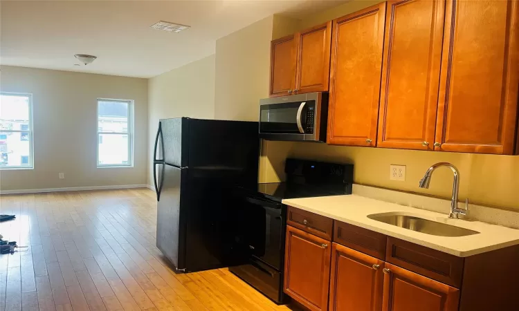 Kitchen featuring sink, light wood-type flooring, and black appliances