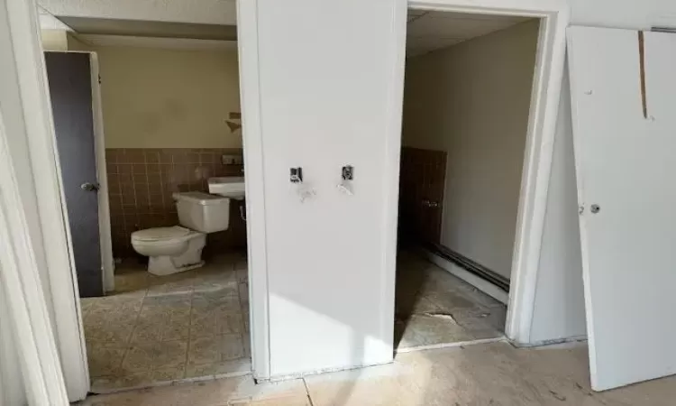 Bathroom featuring tile walls and toilet