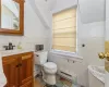 Bathroom featuring toilet, vanity, tile walls, a baseboard heating unit, and lofted ceiling