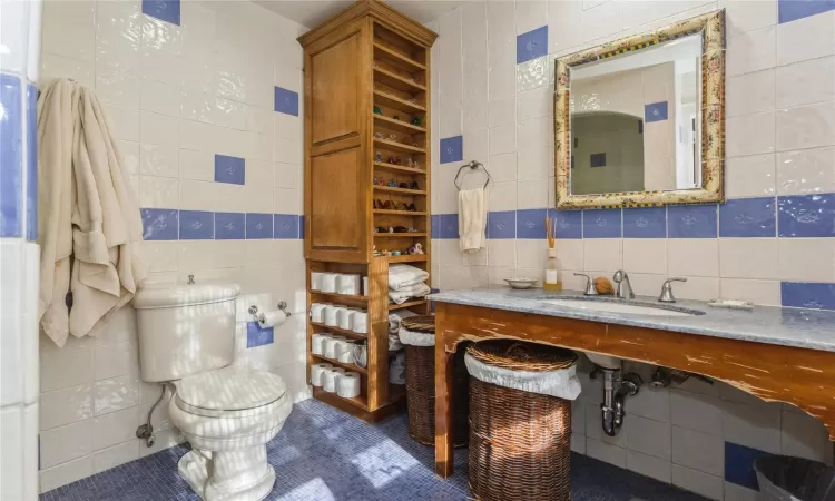 Bathroom with tile walls, toilet, tile patterned floors, and sink