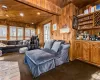 Living room featuring carpet flooring, wooden ceiling, indoor bar, wood walls, and a baseboard radiator