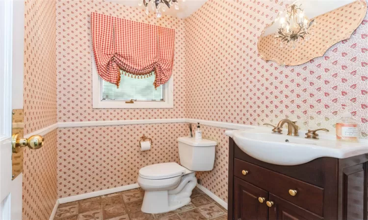 Bathroom featuring an inviting chandelier, vanity, and toilet