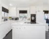 Kitchen with sink, a kitchen island, black appliances, and white cabinetry