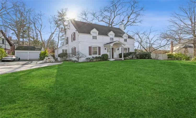 View of front of house featuring an outbuilding, a front lawn, and a garage