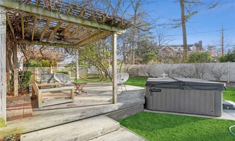 Wooden deck with ceiling fan, a hot tub, and a pergola