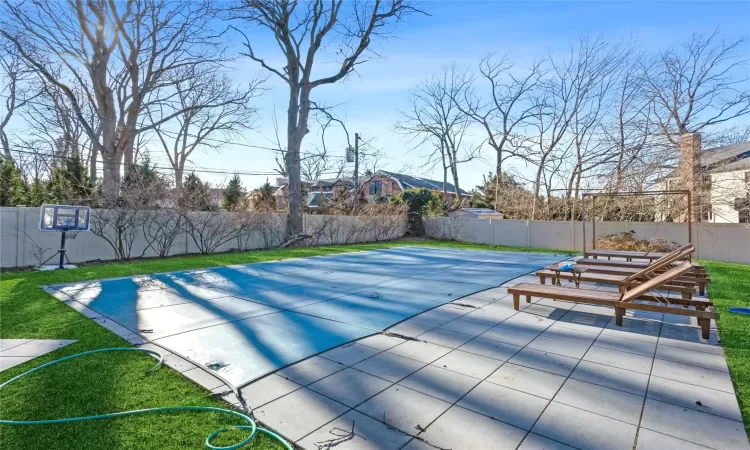 View of swimming pool featuring a yard, a patio area, and basketball hoop