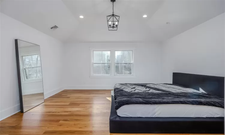 Bedroom with lofted ceiling, a chandelier, and light wood-type flooring