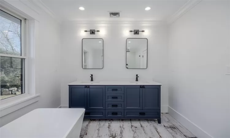 Bathroom with hardwood / wood-style flooring, ornamental molding, a washtub, and vanity