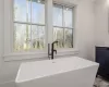 Bathroom featuring a healthy amount of sunlight, a tub, and sink