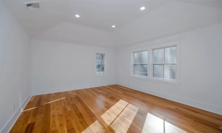 Empty room with vaulted ceiling and wood-type flooring