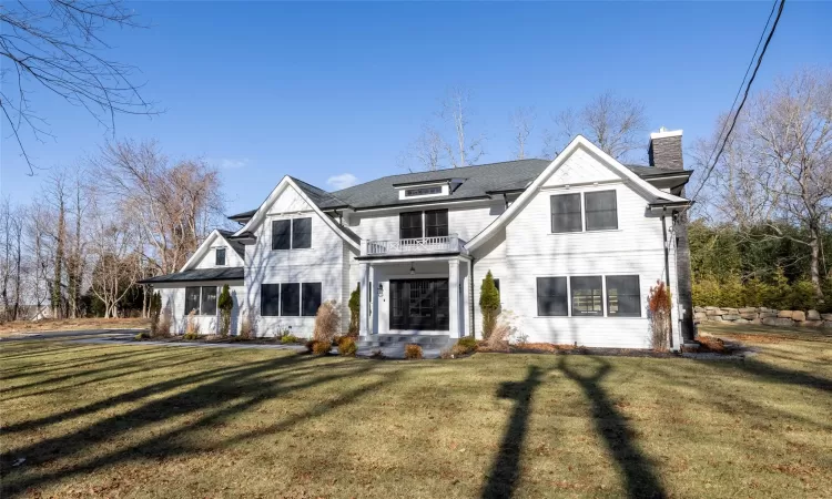 View of front of home featuring a balcony and a front lawn