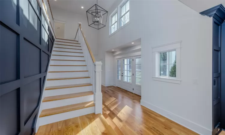 Entryway with a high ceiling, crown molding, a notable chandelier, and light wood-type flooring