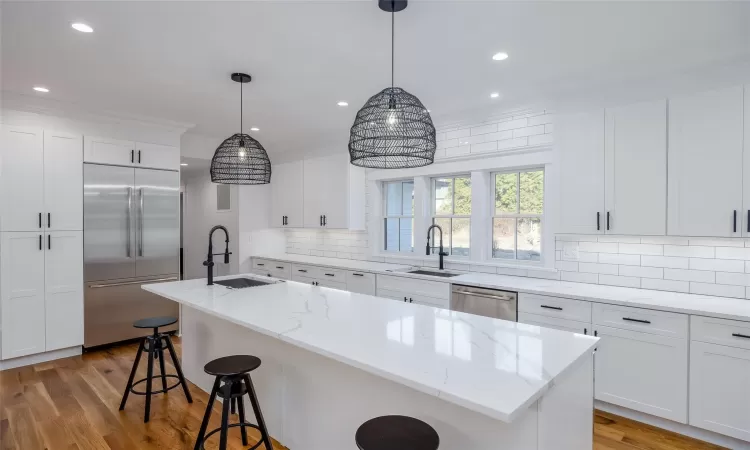 Kitchen featuring appliances with stainless steel finishes, white cabinets, a center island with sink, and sink