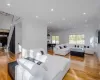 Living room featuring light wood-type flooring, ornamental molding, and a chandelier