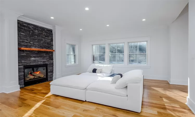 Living room with light wood-type flooring, a fireplace, and ornamental molding