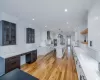 Kitchen featuring tasteful backsplash, sink, a kitchen island with sink, white cabinets, and wall chimney exhaust hood