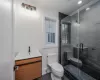 Bathroom featuring toilet, vanity, tile patterned flooring, and a shower with door