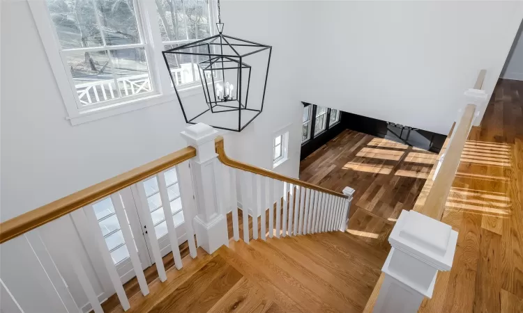 Stairs with hardwood / wood-style flooring and an inviting chandelier