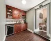 Bar with backsplash, dark hardwood / wood-style floors, dark stone countertops, sink, and beverage cooler