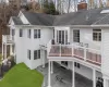 Back of house with a wooden deck, a lawn, and a patio