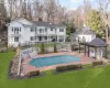 Back of property with a covered pool, a balcony, a yard, a gazebo, and a patio