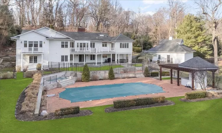 Back of property with a covered pool, a balcony, a yard, a gazebo, and a patio