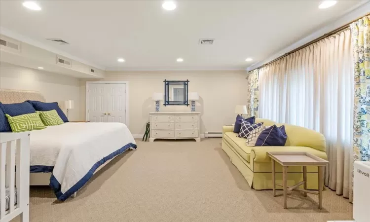 Carpeted bedroom featuring a baseboard heating unit, a closet, and crown molding