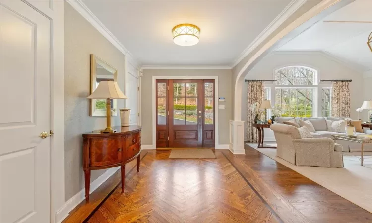 Foyer with ornate columns, lofted ceiling, crown molding, and parquet floors