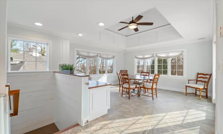 Dining area featuring ceiling fan, ornamental molding, and a raised ceiling