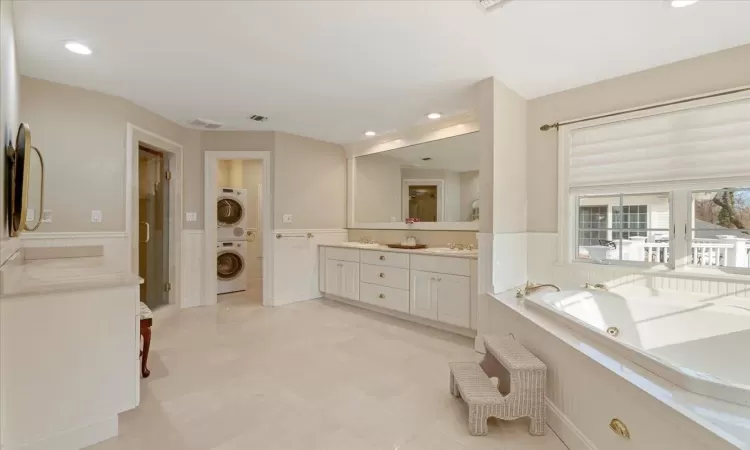 Bathroom featuring vanity, stacked washer and clothes dryer, and a bathing tub