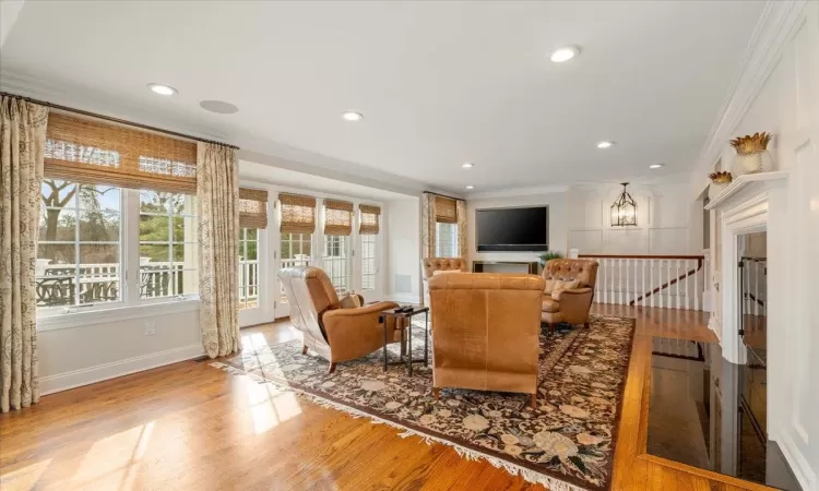 Living room featuring light wood-type flooring, crown molding, and a notable chandelier