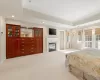 Bedroom featuring light carpet, a high end fireplace, ornamental molding, and a raised ceiling