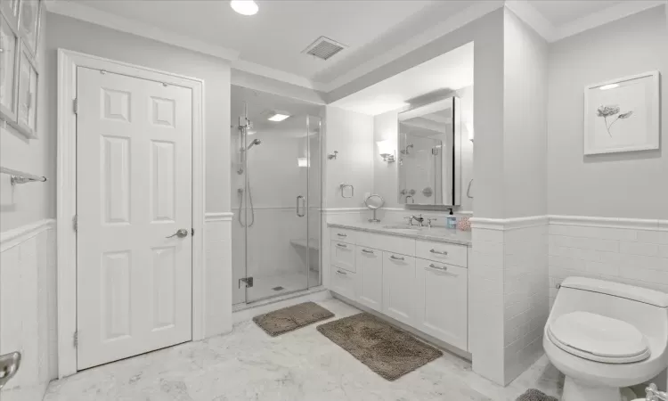 Bathroom with toilet, crown molding, a shower with shower door, and vanity