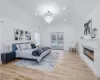 Bedroom featuring an inviting chandelier, access to outside, light hardwood / wood-style floors, and vaulted ceiling