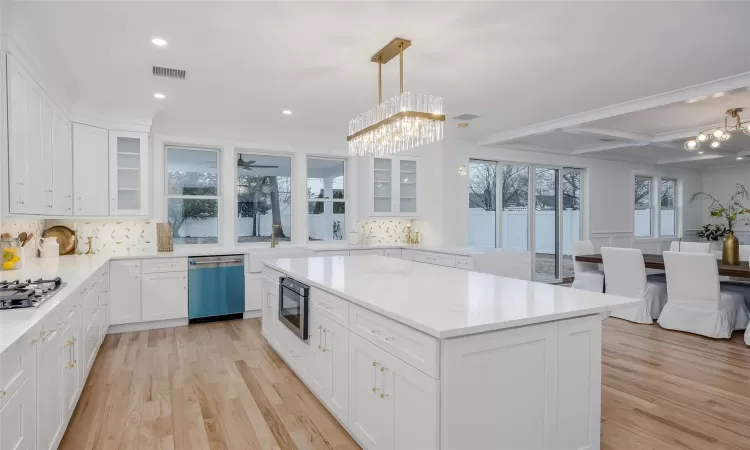 Kitchen featuring white cabinetry, a center island, dishwasher, and tasteful backsplash