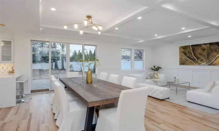 Dining space featuring coffered ceiling, beam ceiling, light hardwood / wood-style floors, and a notable chandelier