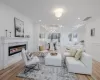 Living room featuring beam ceiling, crown molding, a high end fireplace, and light wood-type flooring