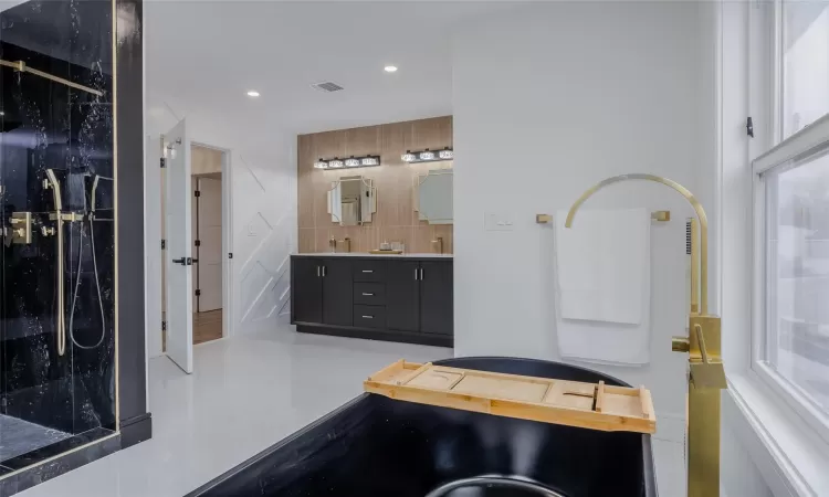 Bathroom with vanity, decorative backsplash, and a shower