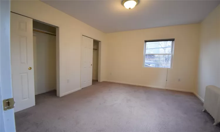 Unfurnished bedroom featuring carpet and radiator heating unit