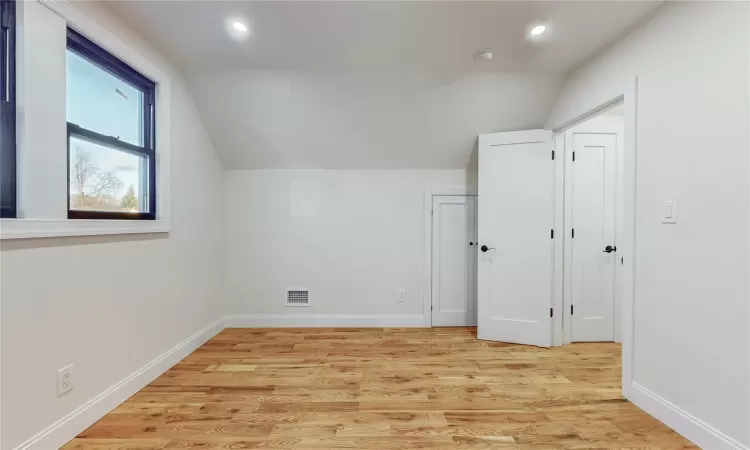 Additional living space featuring light wood-type flooring and vaulted ceiling